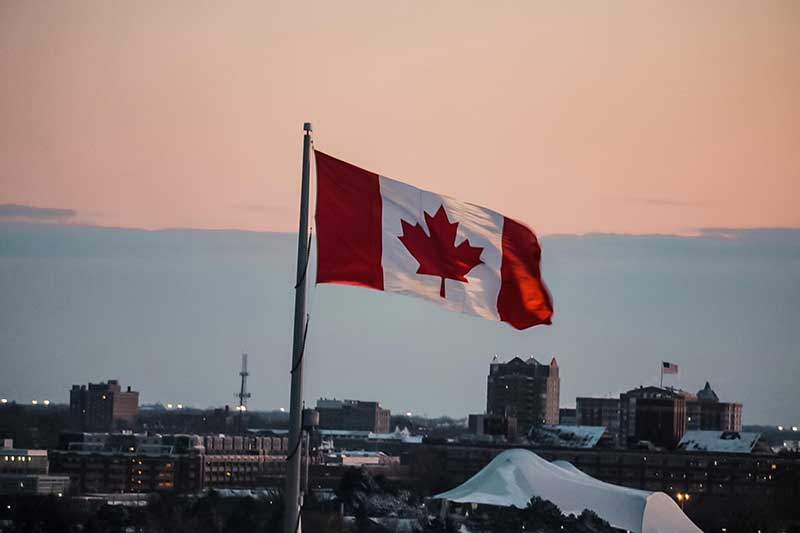 Canadian flag over city by Jose Mier